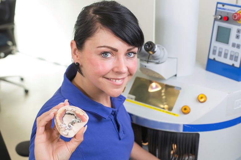 Technician-in-dental-lab-presenting-a-prosthesis-into-the-camera-000025618872_Double.jpg